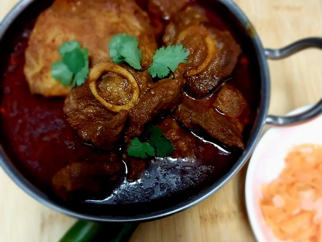 Lamb curry with chops in a steel karahi, served with carrot salad